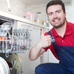 Worker repairing dishwasher in the kitchen