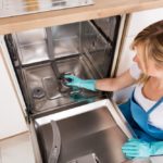 Woman Cleaning Dishwasher In Kitchen