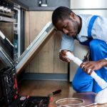 African Handyman Repairing Dishwasher